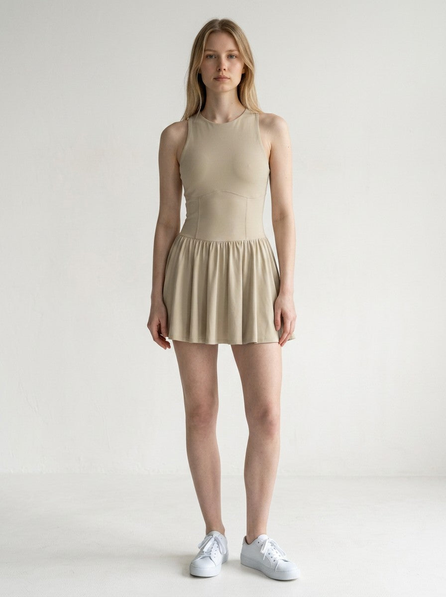 Model wearing a beige EHG SmartWellness sleeveless ruched mini dress with a fitted bodice and flared skirt