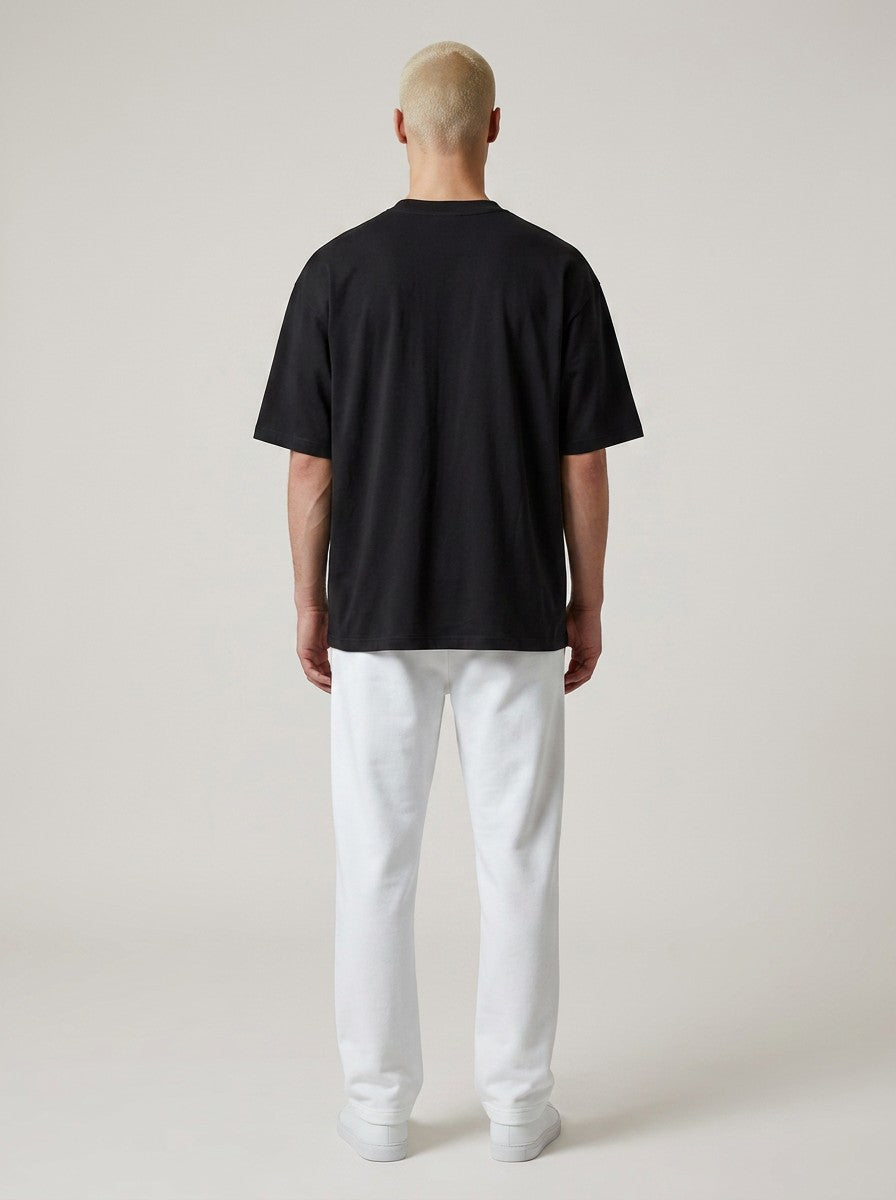 Back view of a man wearing an EHG SmartWellness heavyweight black cotton t-shirt with white trousers.