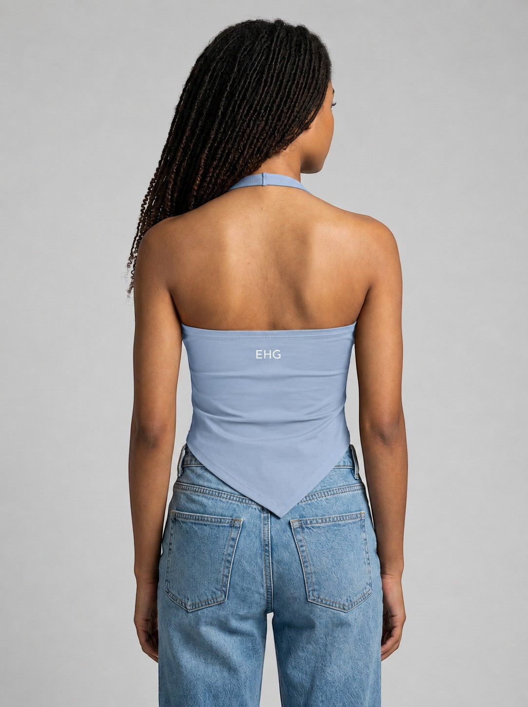 Back view of EHG SmartWellness light blue ruched halter neck yoga tank top with EHG logo, worn with blue jeans.