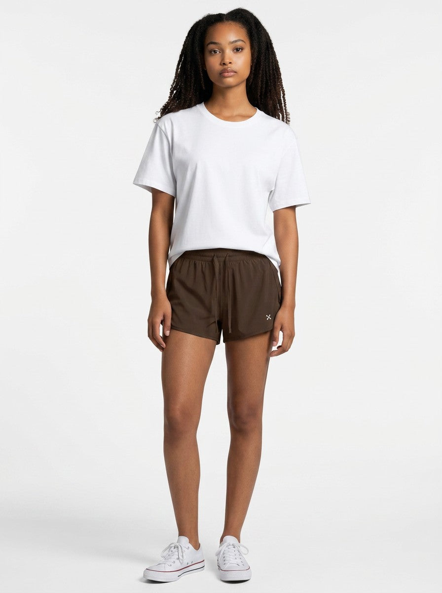 Model wearing EHG SmartWellness brown Bermuda shorts with a drawstring waist and white t-shirt in a studio setting