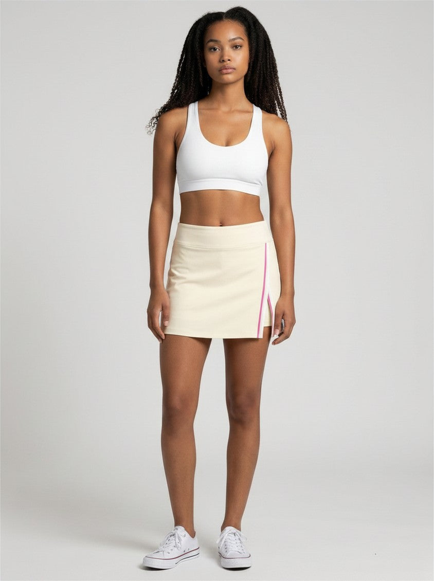 Model wearing EHG SmartWellness cream A-line athletic skirt with pink contrast side panel and slit, paired with top.