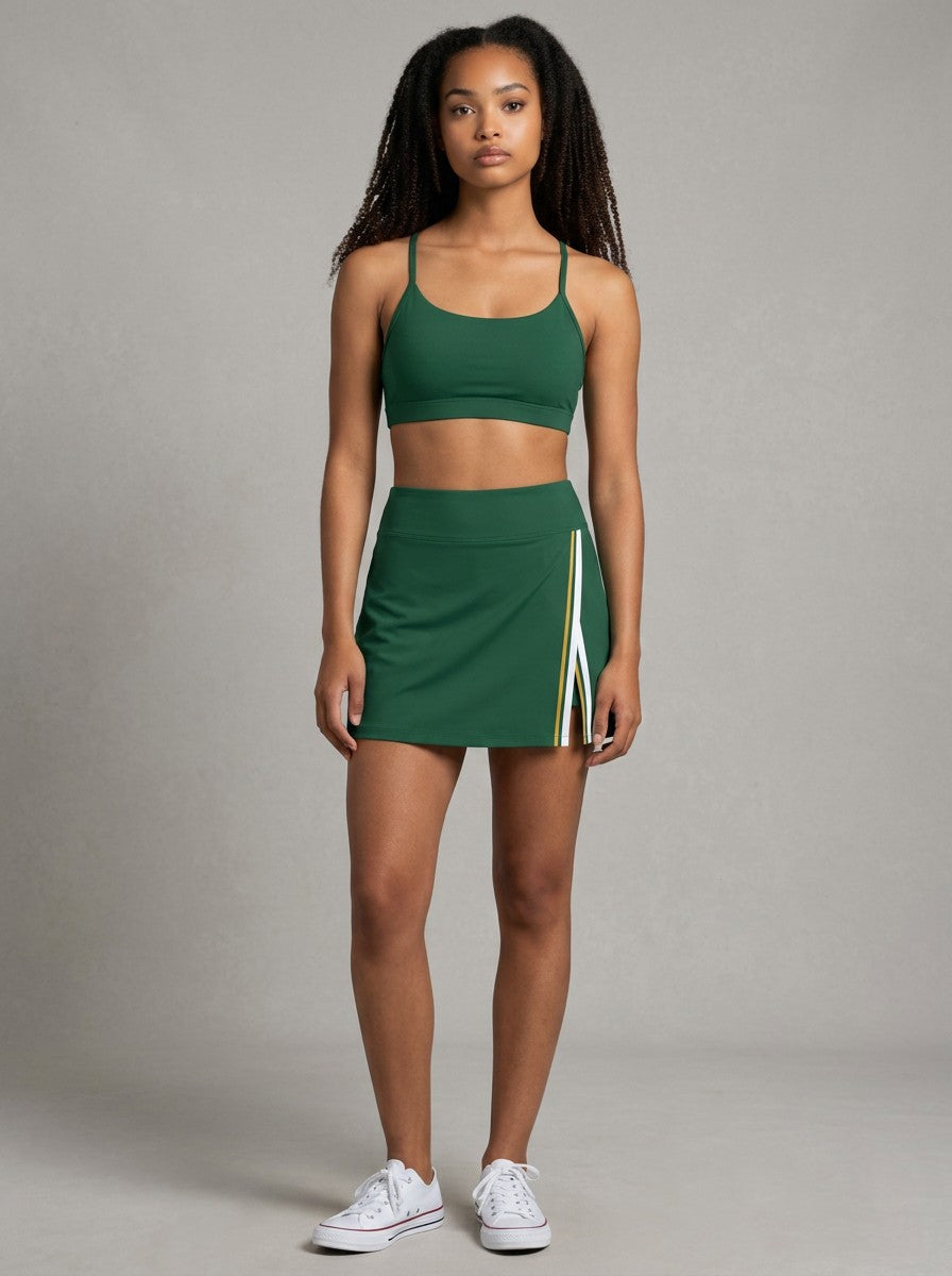 Model wearing EHG SmartWellness green A-line athletic skirt with contrast side panel and slit, paired with sports bra.