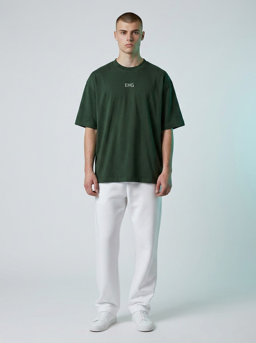 Model wearing an EHG SmartWellness dark green heavyweight cotton t-shirt with white logo and white trousers