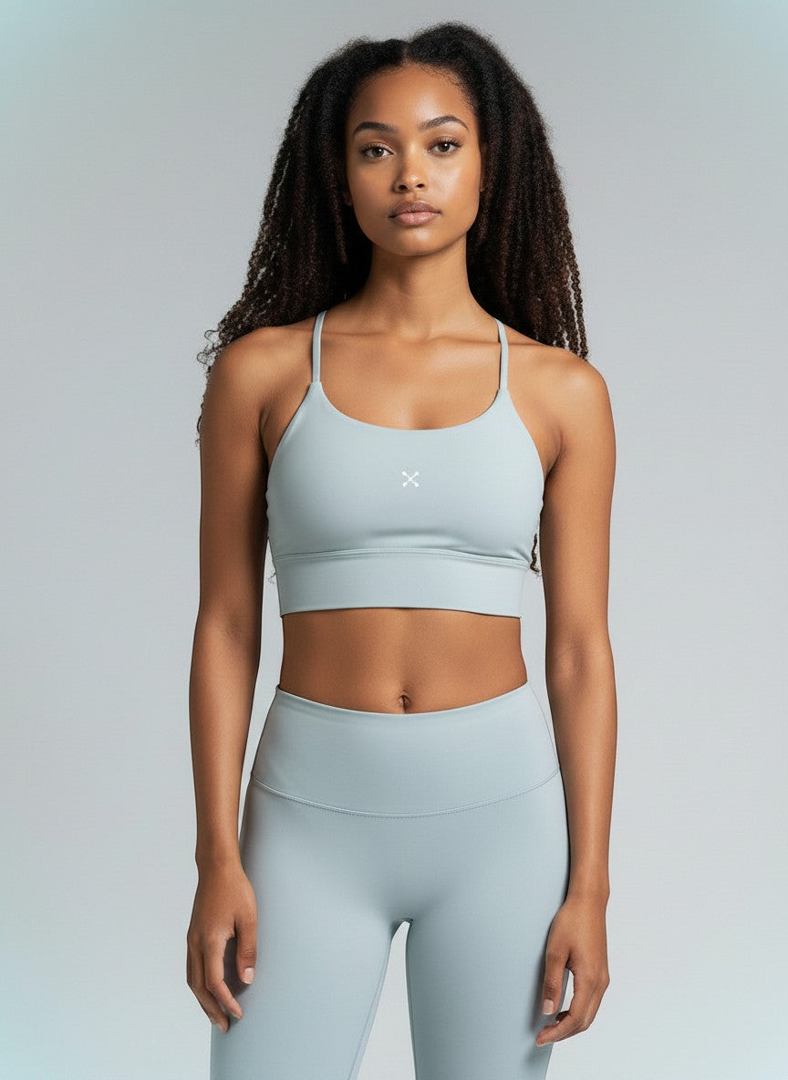 Model wearing a light blue EHG SmartWellness spaghetti strap sports bra with a cropped bodycon fit for yoga.